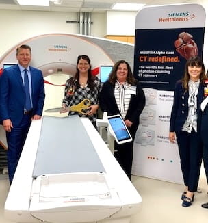 Thumbnail image of Dr. Donna Plecha and others standing next to the new CT scan machine.