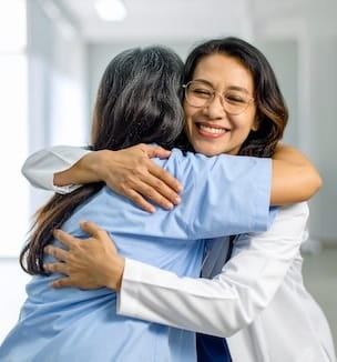Thumbnail image of a female doctor hugging her patient.