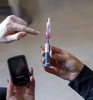 Thumbnail image of a woman's hand holding on to an insulin tube.