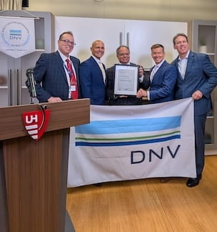 Thumbnail image of DNV and UH holding the ISO 9001 certificate and flag during a presentation.