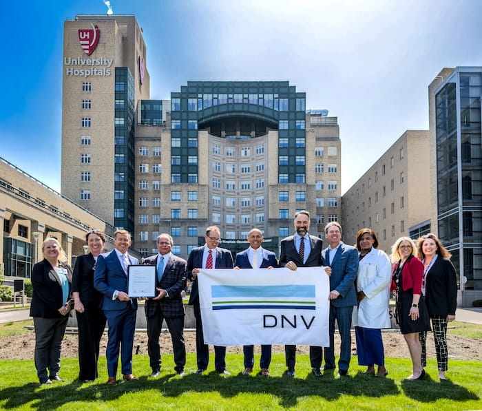 Group shot of people holding the ISO 9001 banner in front of Cleveland Medical Center.