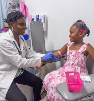 Smiling female doctor getting a blood sample from a female pediatric patient.