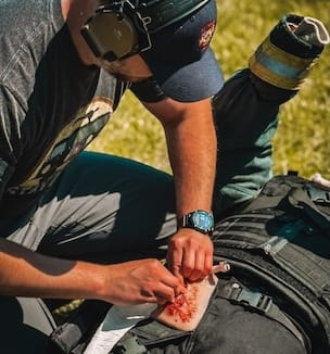 Thumbnail image of firefighter practicing first aid to someone who is bleeding.