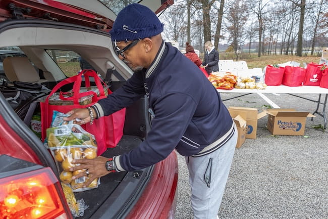 Image of a UH employee loading groceries into the back of a car.
