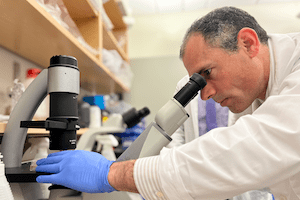 Scientist looking through microscope in research lab.